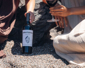 a bottle of red wine held in the sand